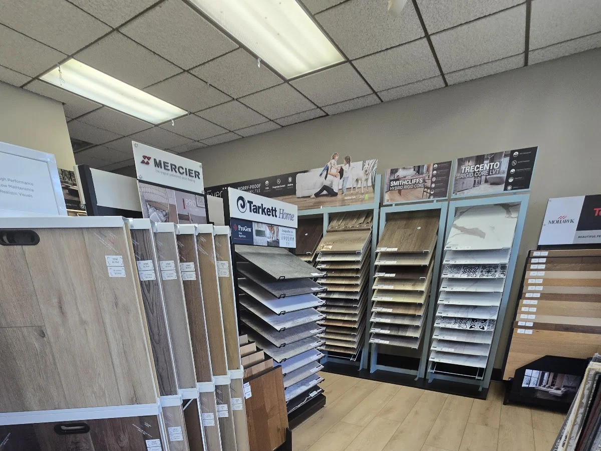 Showroom aisle with Mercier, Tarkett, and other flooring sample racks over a light wood floor